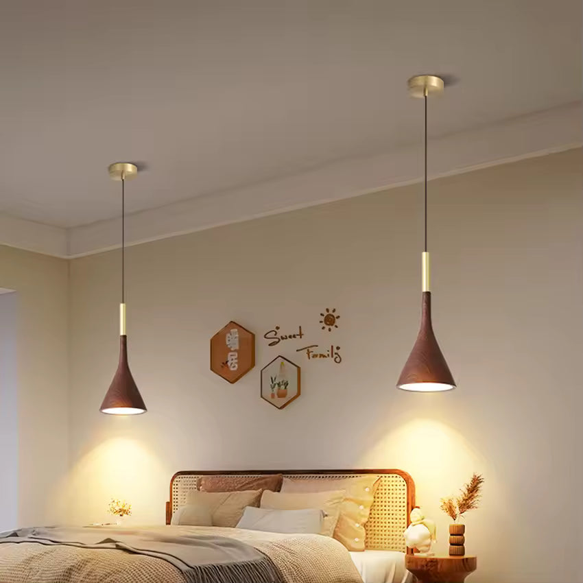 Deux suspensions effet noyer et laiton encadrent le lit et diffusent une lumière douce dans une chambre naturelle