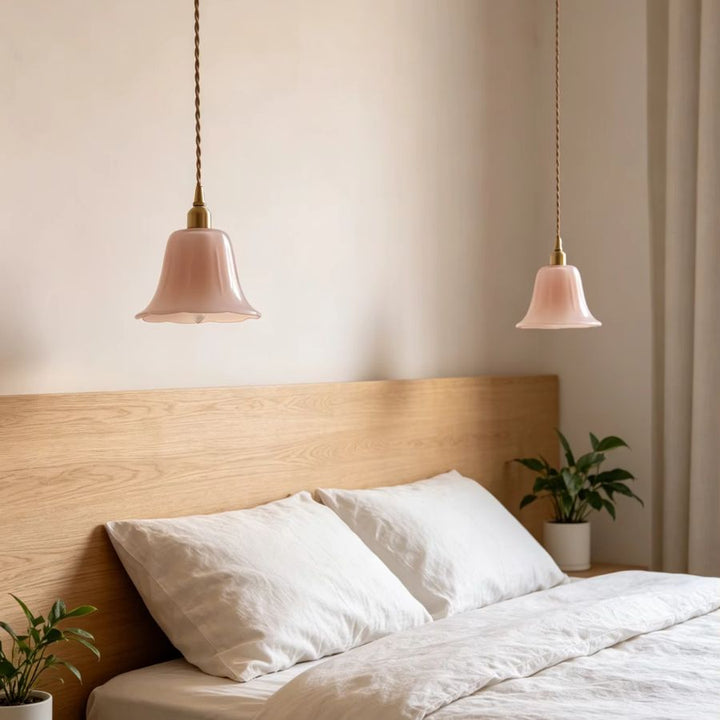 Deux suspensions fleur en verre soufflé rose encadrent le lit dans une chambre douce au style romantique et vintage