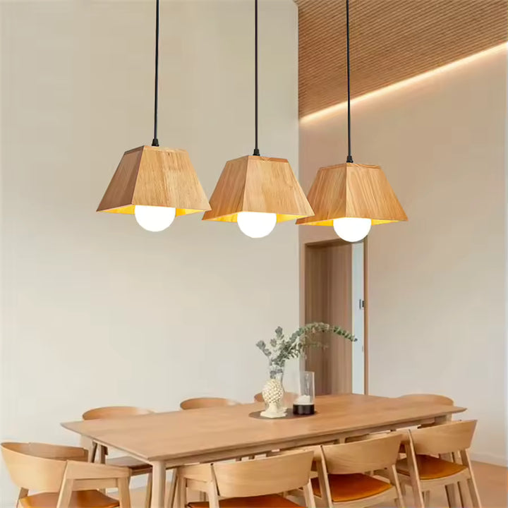 Trois suspensions en bois géométriques à globe opalin, au-dessus d’une table dans un décor japandi chaleureux
