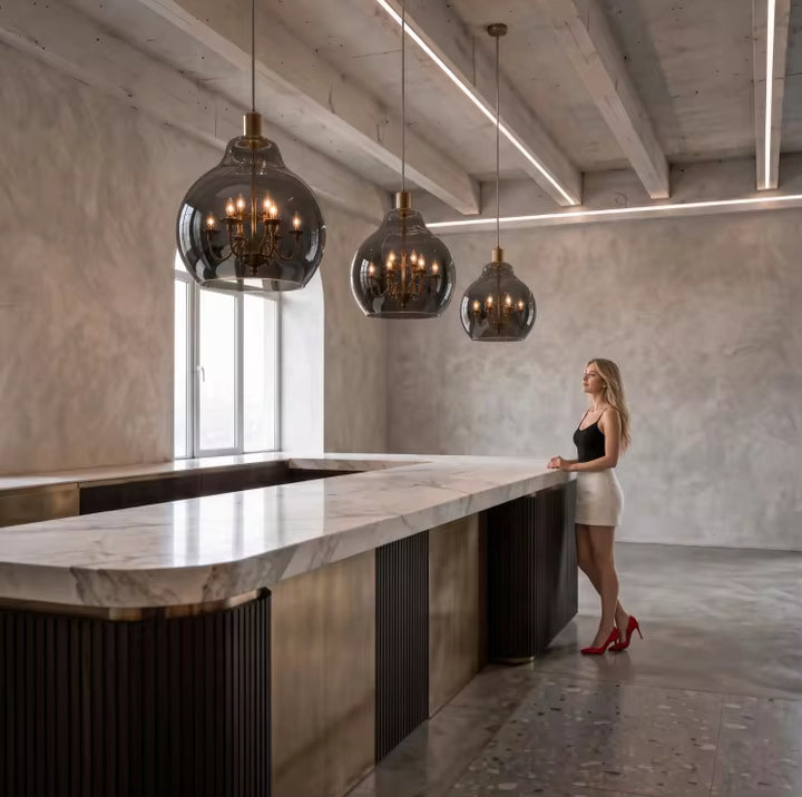 Alignement de suspensions globe en verre fumé avec lustres dorés au-dessus d’un îlot au style contemporain