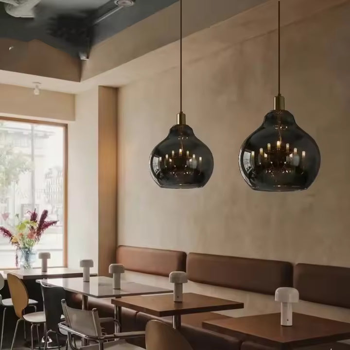 Deux suspensions globe en verre fumé noir avec lustres dorés, installées dans un intérieur contemporain élégant