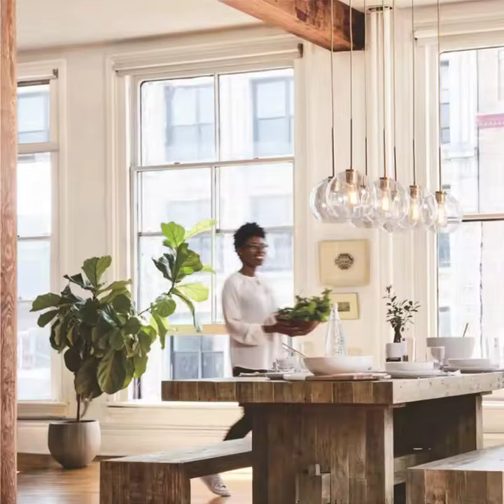 En série au-dessus d’un îlot de cuisine, suspensions en verre transparent au style moderne et lumineux
