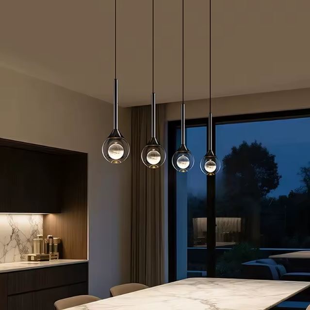 Suspensions goutte en verre et métal noir en ambiance nocturne, éclairage design contemporain pour salle à manger élégante.