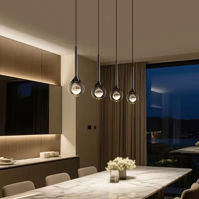 Suspensions goutte en verre et métal noir au-dessus d’une table, éclairage de salle à manger au style contemporain et haut de gamme.