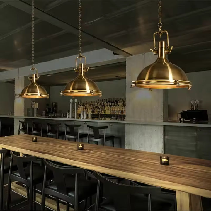 Suspensions dorées de style industriel vintage installées au-dessus d’une grande table de bar