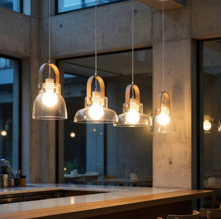 Quatre suspensions en bois et verre soufflé transparent illuminent un comptoir dans un décor contemporain chaleureux