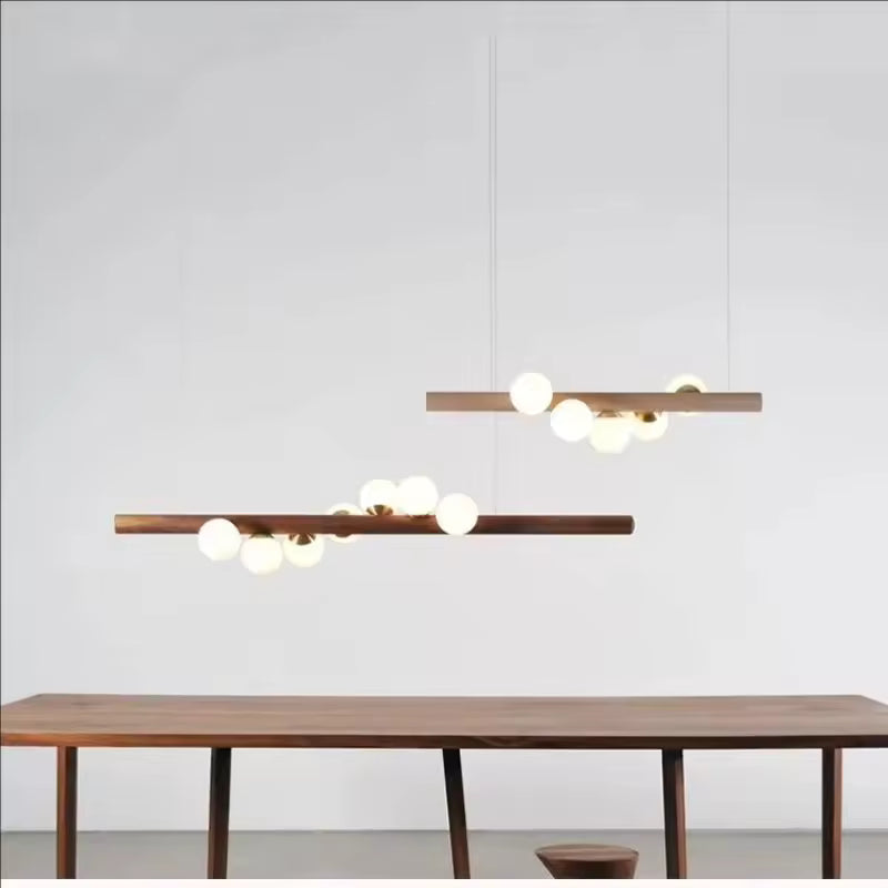 Deux suspensions linéaires en bois à globes lumineux, dans une composition minimaliste aux influences scandinaves et japandi.