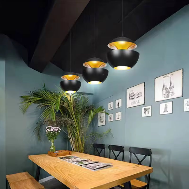 Alignement de suspensions noires à double coque et intérieur doré dans une salle à manger au style moderne
