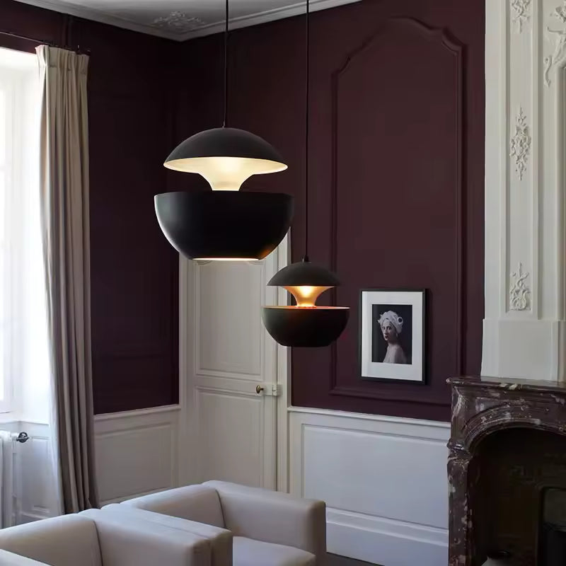 Deux suspensions noires à double coque métallique dans un salon élégant, au design sculptural et contemporain