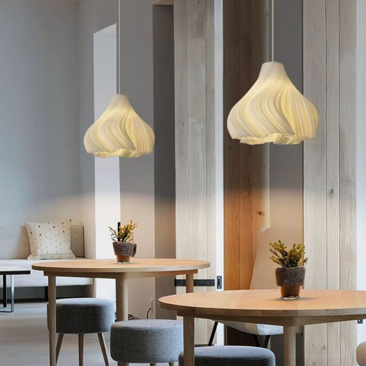 Suspensions aux courbes plissées dans un intérieur en bois clair, entre design organique, contemporain et japandi