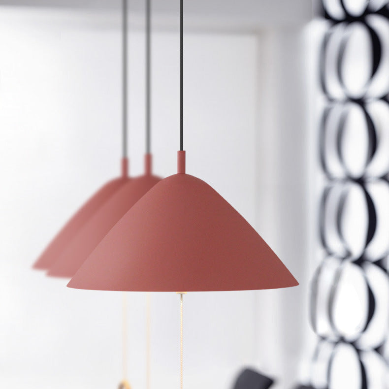 Suspensions roses au design danois alignées dans une salle à manger contemporaine.