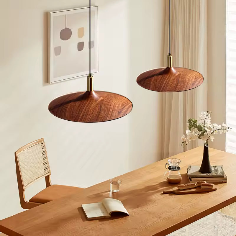 Deux suspensions soucoupe effet bois au-dessus d’une table, design scandinave aux lignes organiques