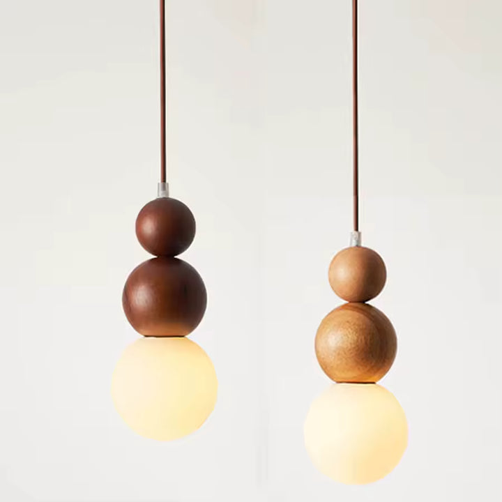 Deux suspensions totem en bois clair et foncé avec globe opalin, au design organique et sculptural d’inspiration japandi