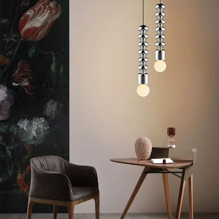 Deux suspensions totem en métal chromé apportent une touche design, contemporaine et sculpturale au bureau