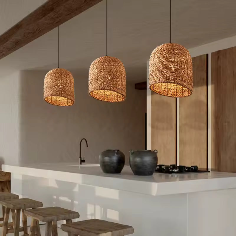Trois suspensions tressées en fibre naturelle au style méditerranéen, alignées au-dessus d’un îlot de cuisine