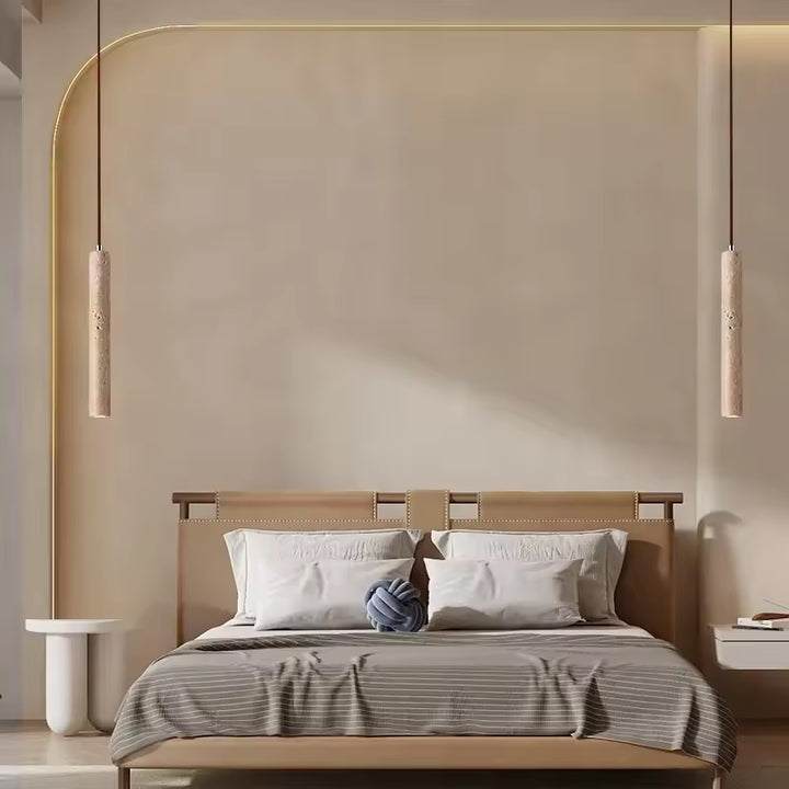 Deux suspensions tube en travertin encadrant un lit dans une chambre design aux lignes minimalistes