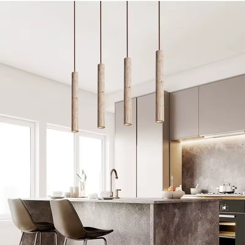 Quatre suspensions tube en travertin alignées au-dessus d’un îlot de cuisine au design contemporain épuré