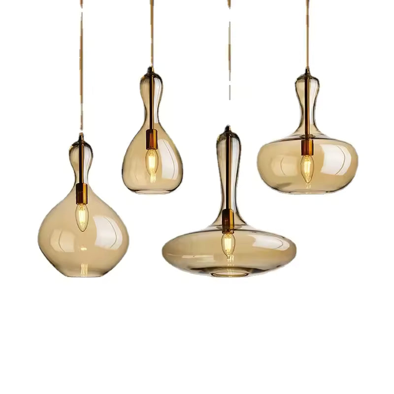 Quatre modèles de suspensions en verre ambré aux formes de goutte et de galet, avec ampoules apparentes et design sculptural.