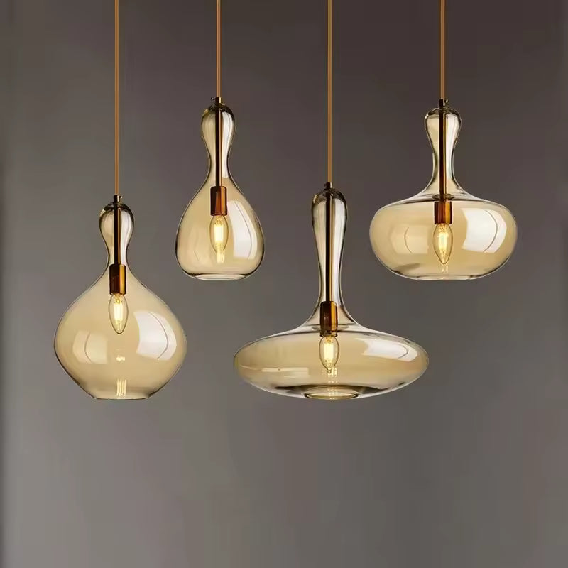 Quatre suspensions en verre ambré aux formes de goutte et de galet, mêlant design organique et élégance contemporaine.