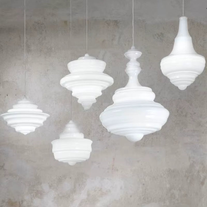 Cinq suspensions en verre blanc opalin aux formes sculpturales et reliefs étagés, dans un décor contemporain épuré.