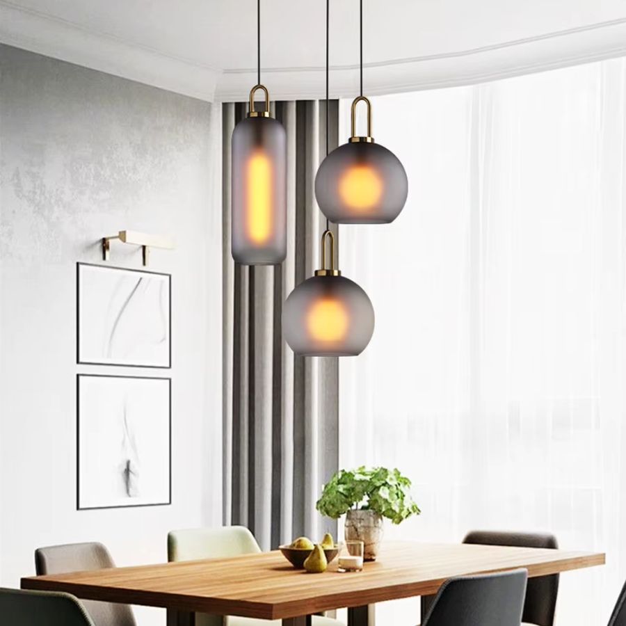 Suspensions en verre fumé à anse dorée au-dessus d’une table de salle à manger au style chic et contemporain