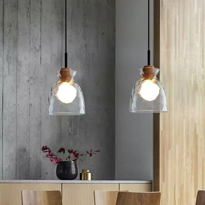 Deux suspensions en verre ondulé et bois dans une salle à manger, au style japandi sobre et chaleureux