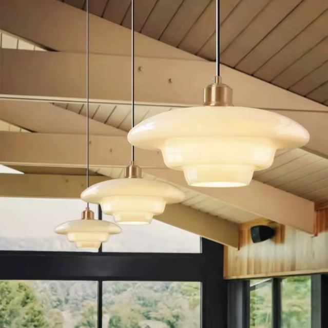 Trio de suspensions en verre opaline éclairant un intérieur chaleureux avec un design moderne et lumineux.