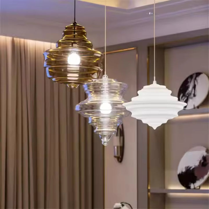 Trio de suspensions en verre ambré, transparent et blanc opalin, aux reliefs étagés et au design contemporain.