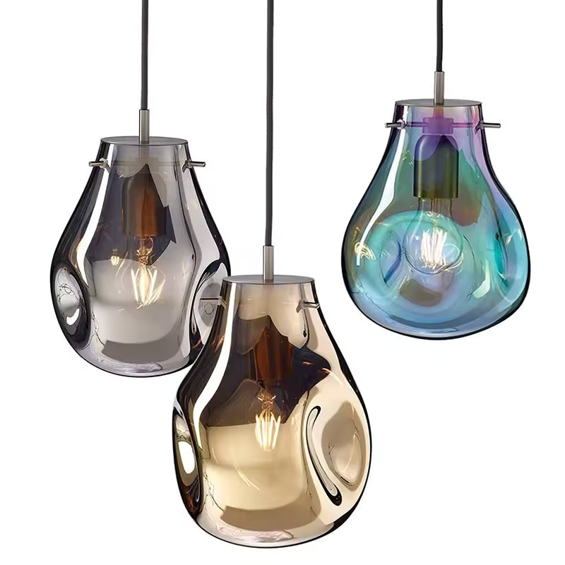 Trois suspensions sculpturales en verre soufflé fumé, ambré et irisé dévoilent leurs courbes fluides et ampoules apparentes.