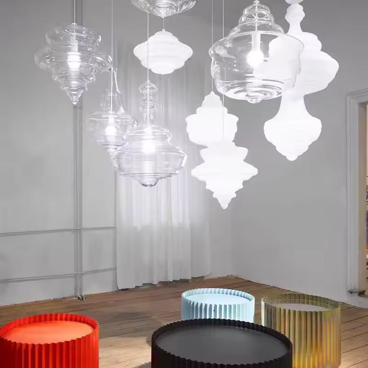 Composition aérienne de suspensions sculpturales en verre transparent et blanc opalin, aux reliefs superposés et formes variées.