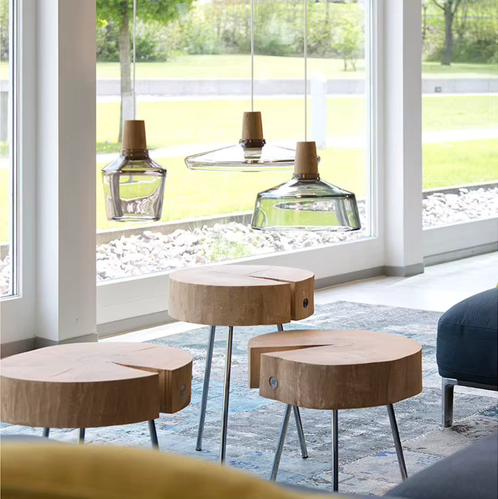 Devant une large baie vitrée, trois luminaires en verre transparent et bois apportent une touche naturelle et contemporaine