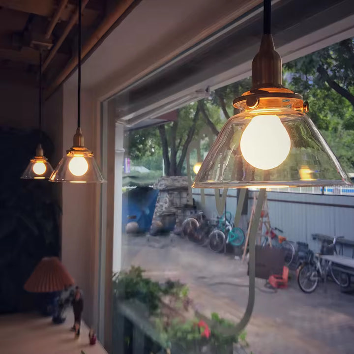 Alignement de suspensions en verre transparent et laiton, au style rétro industriel avec lumière chaude