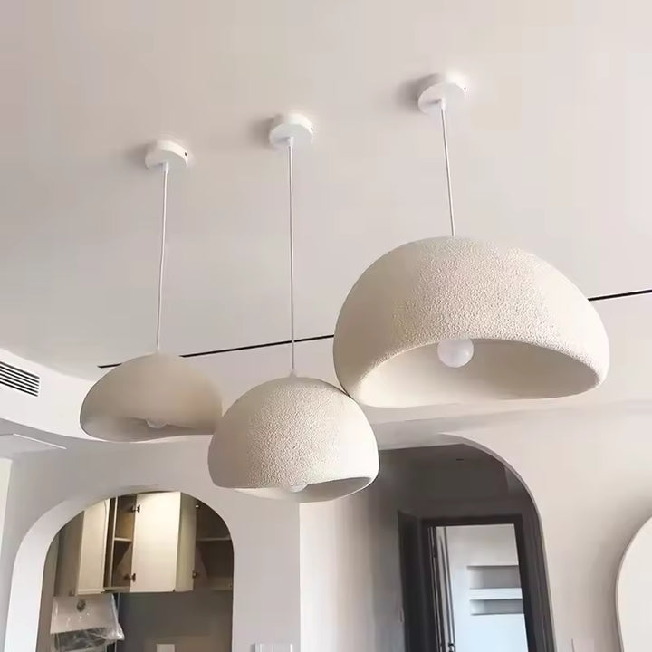 Trois suspensions wabi-sabi blanches aux dômes asymétriques et texturés, dans un intérieur moderne aux arches arrondies.