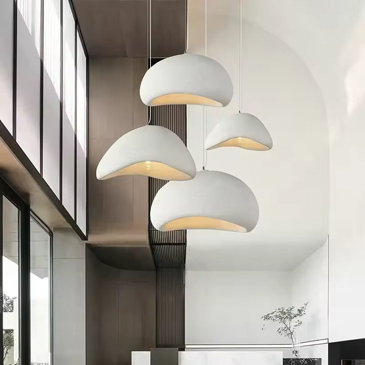 Quatre suspensions blanches aux dômes asymétriques habillent un plafond haut dans une entrée contemporaine au design épuré.