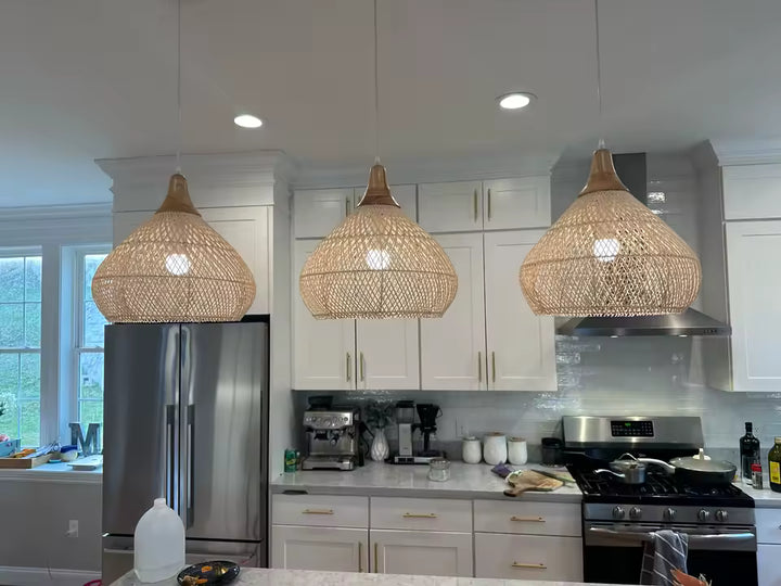 Dans cette cuisine lumineuse, trois suspensions en rotin naturel créent une ambiance bohème, chaleureuse et authentique
