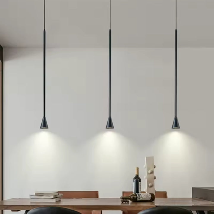 Trois suspensions noires élancées à embout trompette éclairent une table de salle à manger au style minimaliste