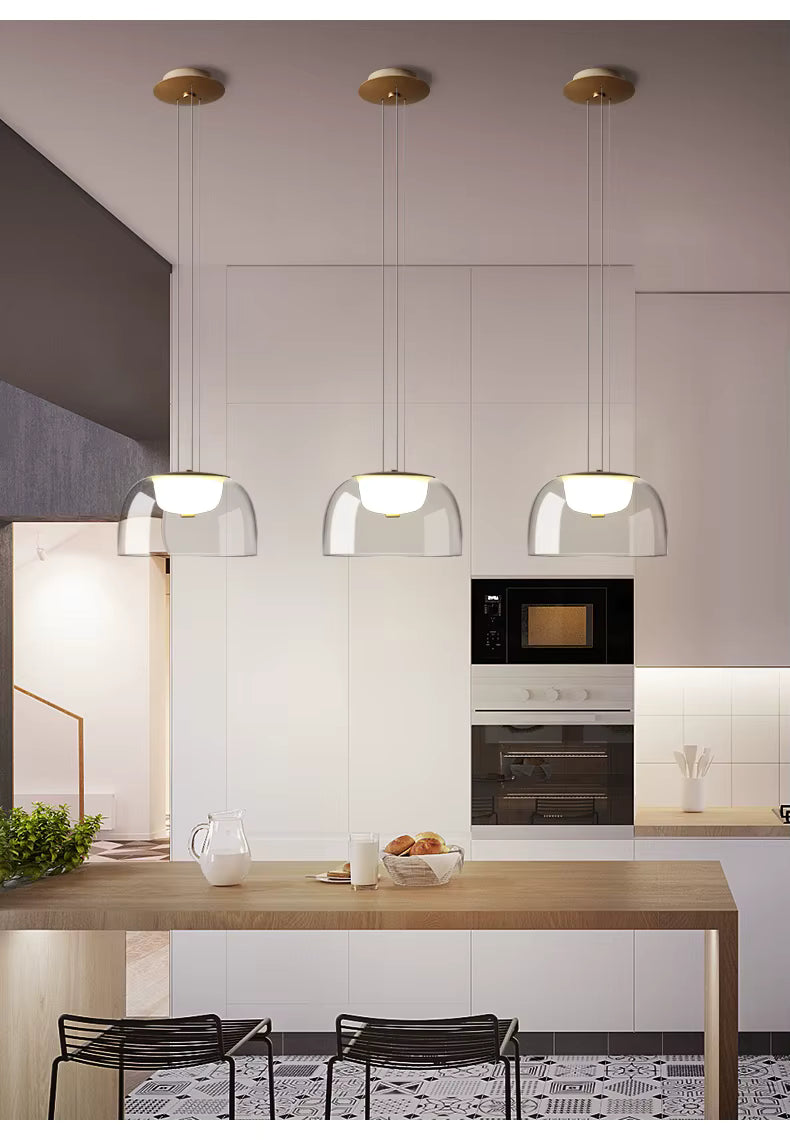 Alignées au-dessus d’un îlot, trois suspensions en verre transparent à diffuseur opalin soulignent un style moderne et minimaliste