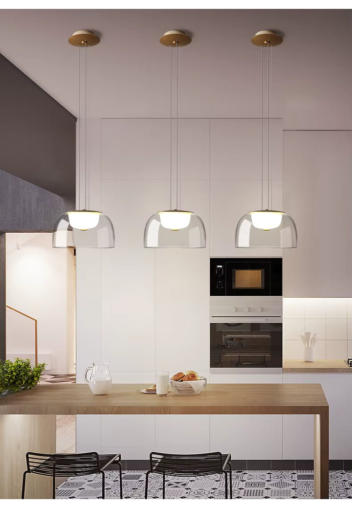 Alignées au-dessus d’un îlot, trois suspensions en verre transparent à diffuseur opalin soulignent un style moderne et minimaliste