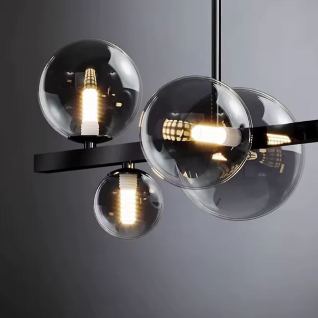 Gros plan sur une suspension design avec globes en verre fumé et éclairage LED, révélant un style moderne et épuré idéal pour un intérieur contemporain.