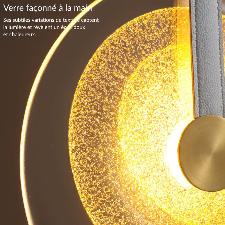 Détail du verre texturé d’une suspension médaillon à lanière en cuir, au rendu chaleureux et sophistiqué