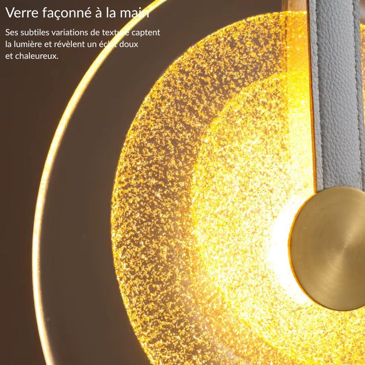 Détail du verre texturé d’une suspension médaillon à lanière en cuir, au rendu chaleureux et sophistiqué