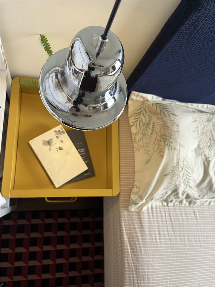 Vue plongeante sur la cloche en métal chromé, installée près d’un chevet dans un intérieur au style vintage raffiné