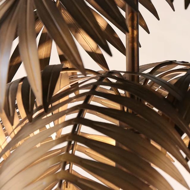 Zoom sur les feuilles de la suspension palmier en métal cuivré, révélant les détails texturés et la finition soignée.