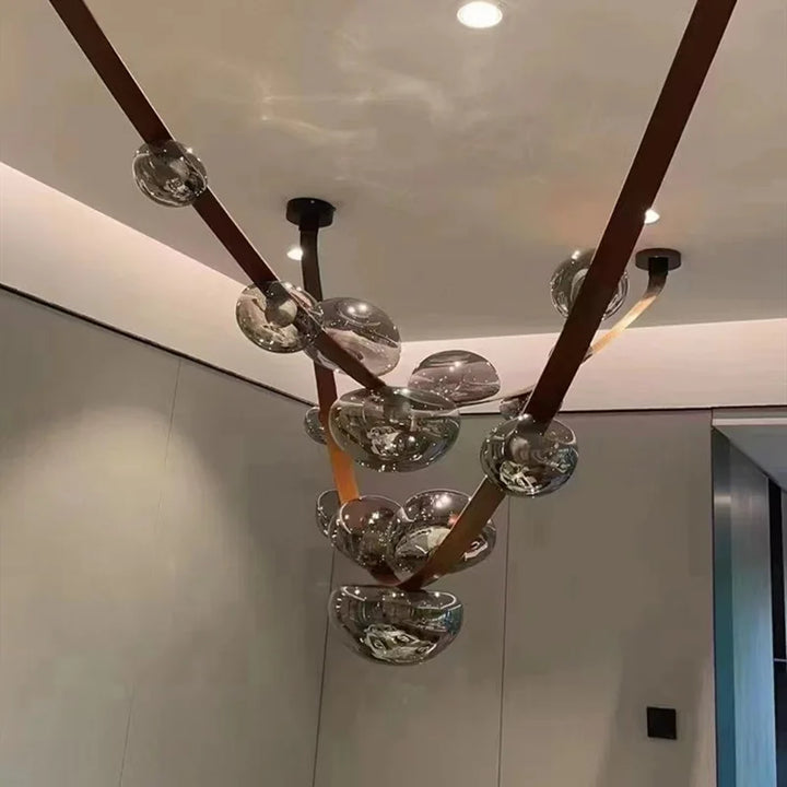 Gros plan artistique sur les finitions en cuir et les sphères lumineuses en verre fumé aux reflets dorés subtils.